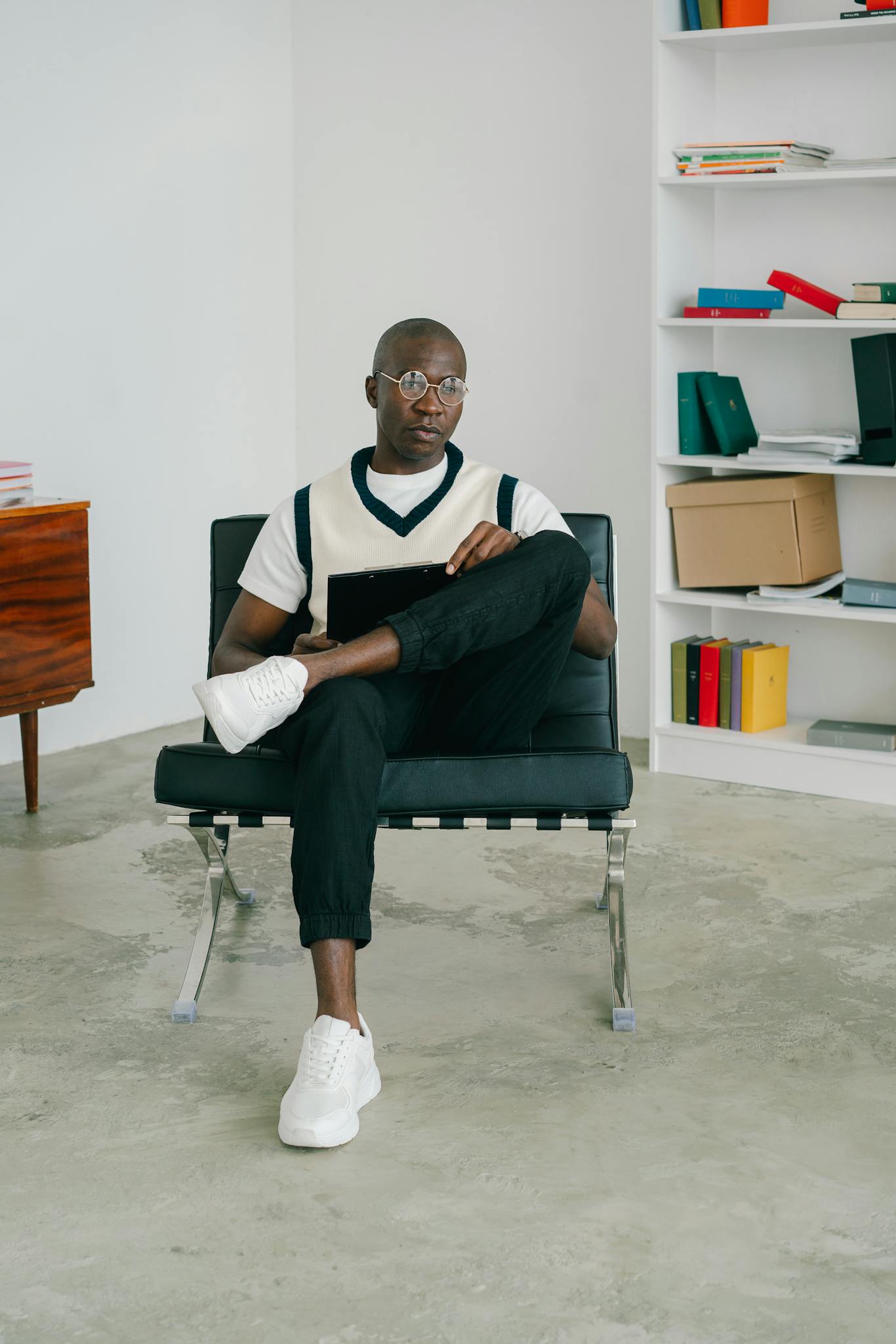 African American man sitting on a chair in a contemporary office space with bookshelves.
